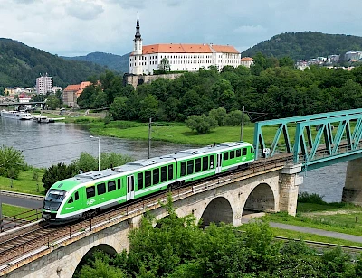 Ein neuer Desiro-Triebzug fährt vor der Kulisse des Schlosses Děčín auf der Brücke über die Elbe.